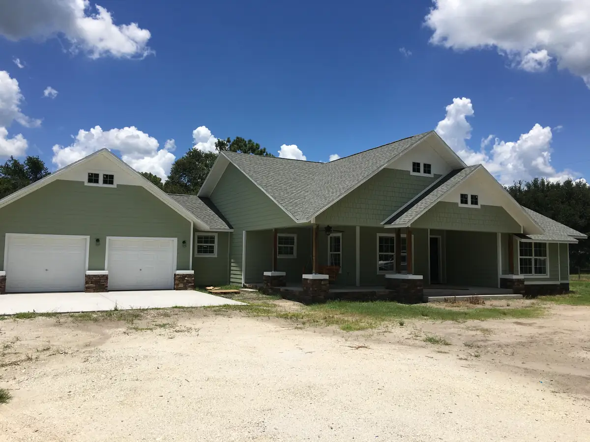Newly completed craftsman-style custom home with a side-entry garage wing, before landscaping