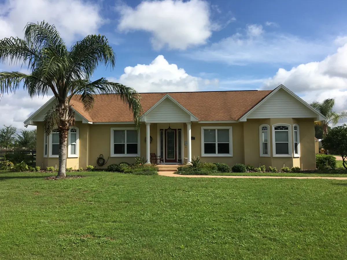 Completed custom home with a tile roof and mature landscaping