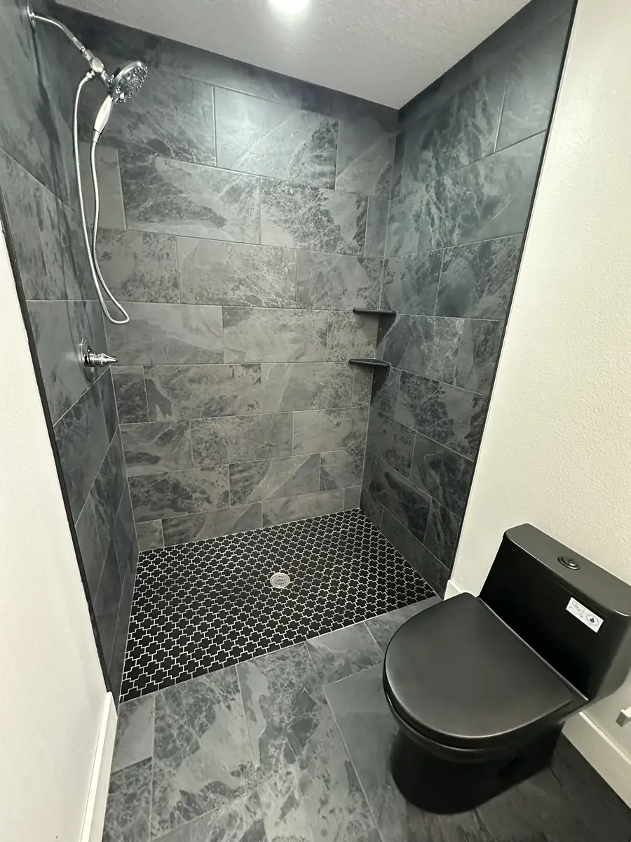 Grey stone-look tiled walk-in shower with a mosaic tile floor