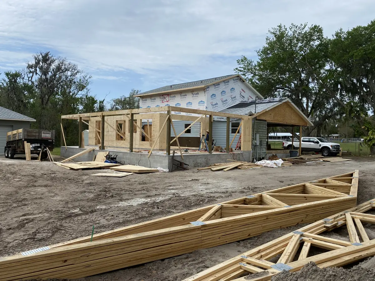 Room addition framed on a block stem wall with roof trusses stacked ready to set