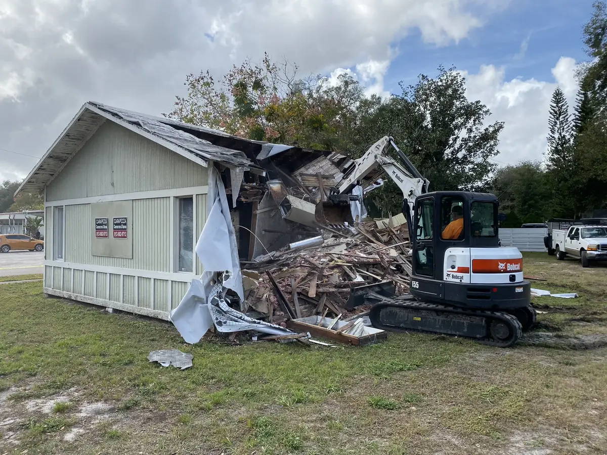 Selective demolition of a single-storey cottage with a wall opened and debris stacked