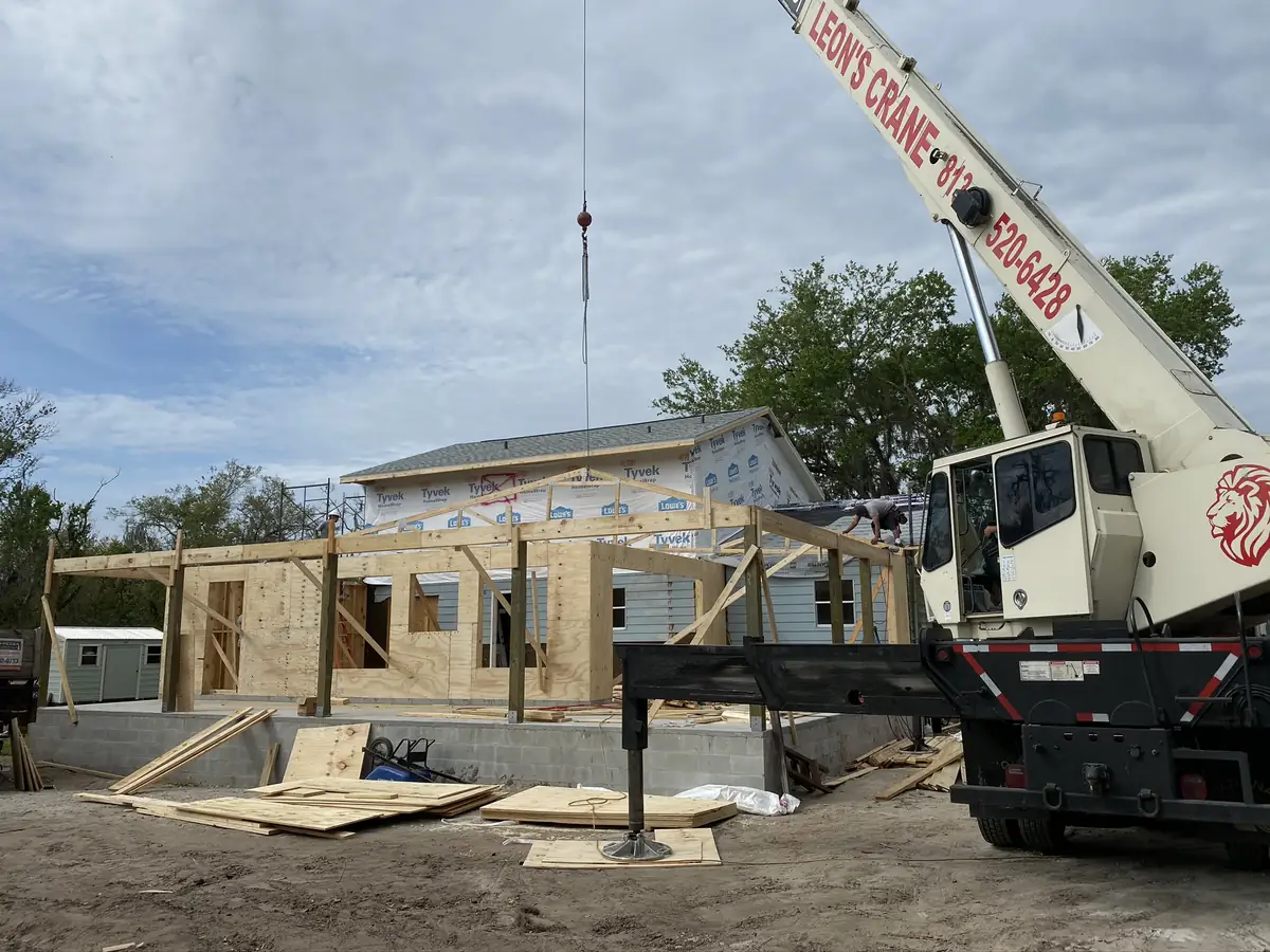 Crane setting roof trusses on a home under construction