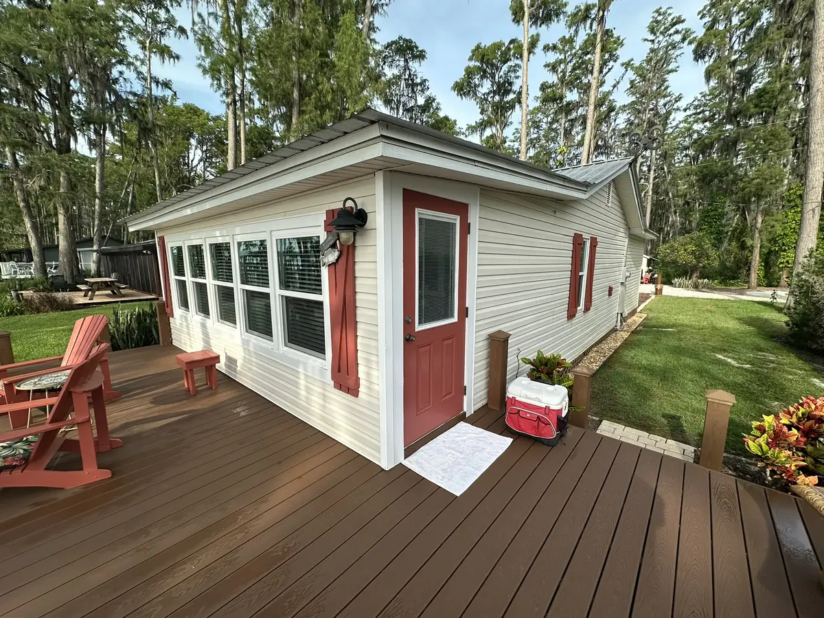 Cottage with new siding, a red front door, and a rebuilt deck