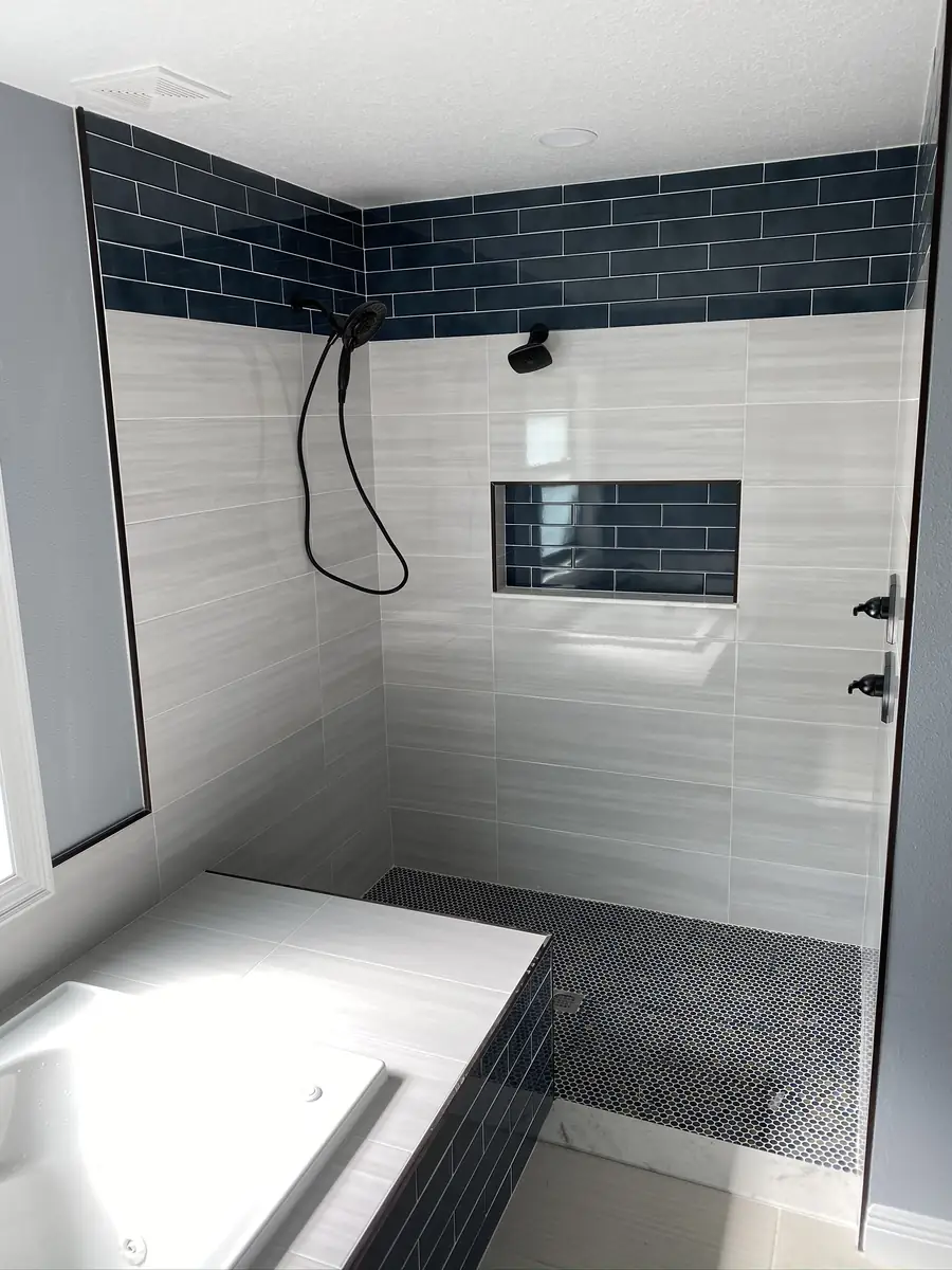 Tiled walk-in shower with a recessed niche and a dark accent band