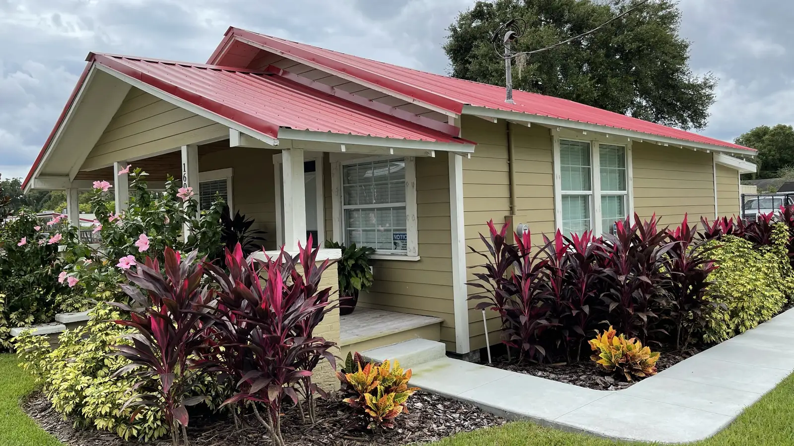 An older bungalow after an exterior remodel, with a new standing-seam metal roof, repainted siding and fresh landscaping along the walk